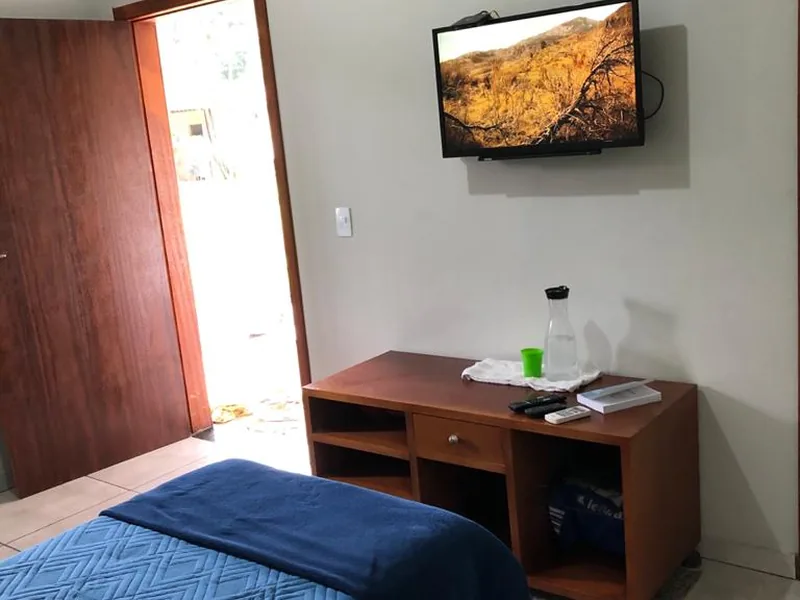 Quarto com cama arrumada, televisão e armário