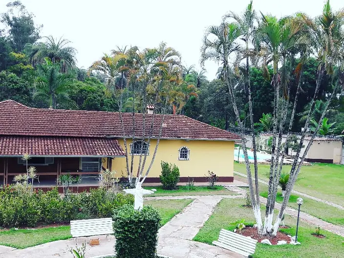 Casa de alvenaria com jardim, palmeiras e caminho de pedra