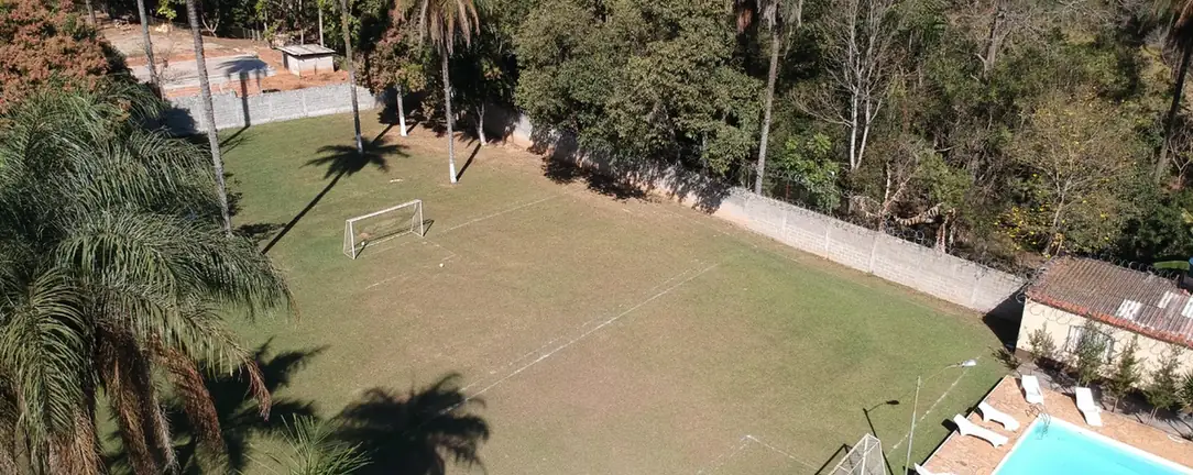 Vista de cima da área da estrutura, com quadra, piscina e árvores