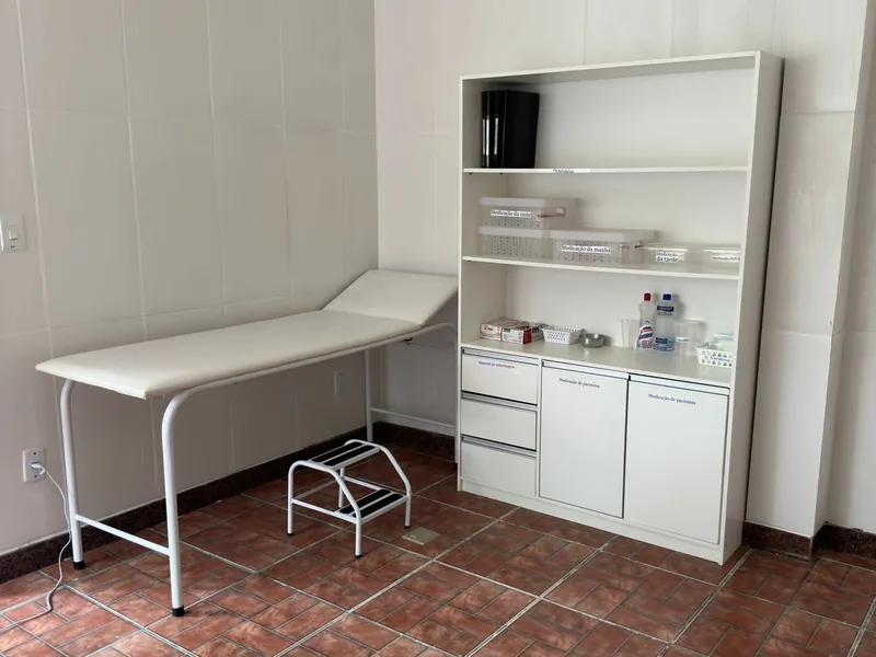 Sala de enfermaria com maca e armário de medicamentos