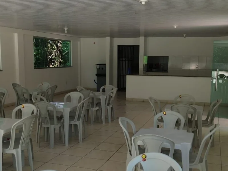 Refeitório com mesas e cadeiras e balcão ao fundo